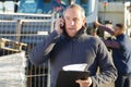 Mature builder with telephone outside on work site