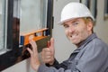 mature builder using spirit level and making thumbs up gesture Royalty Free Stock Photo