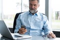 Mature business man in formal clothing using mobile phone. Serious businessman using smartphone at work. Manager in suit