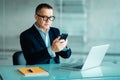 Mature business man in formal clothing wearing spectacles using mobile phone. Serious businessman using smartphone at work. Manage Royalty Free Stock Photo