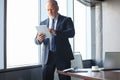 Mature business man in formalwear using digital tablet while standing in the office Royalty Free Stock Photo