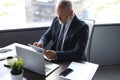 Mature business man in full suit using digital tablet while sitting in the office Royalty Free Stock Photo