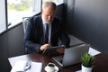 Mature business man in full suit using digital tablet while sitting in the office Royalty Free Stock Photo