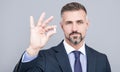 mature business man with grizzled hair in suit hold pill in hand with ok gesture, energy remedy