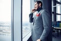 Mature business man standing inside office building and using cell phone. Man standing by window and talking on mobile Royalty Free Stock Photo