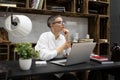 mature business woman at the workplace sitting in glasses thinking in front of an open laptop Royalty Free Stock Photo