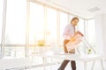 Mature businessman carrying chair wrapped in plastic at new office with yellow lens flare in background