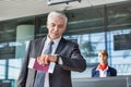Mature businessman checking time on his watch after checked in at airport Royalty Free Stock Photo