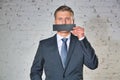 Mature businessman covering mouth with paper against white brick wall at office Royalty Free Stock Photo