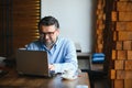 Mature businessman drinking coffee in cafe. Portrait of handsome man wearing stylish eyeglasses using laptop, looking at Royalty Free Stock Photo