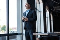 Mature businessman drinking water and looking out of a window at the city from an office building. Royalty Free Stock Photo