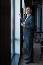 Mature businessman drinking water and looking out of a window at the city from an office building. Royalty Free Stock Photo