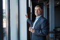 Mature businessman drinking water and looking out of a window at the city from an office building. Royalty Free Stock Photo