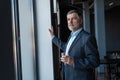 Mature businessman drinking water and looking out of a window at the city from an office building. Royalty Free Stock Photo