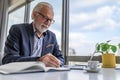 Mature businessman or entrepreneur working on laptop computer and taking notes and writing. Handsome senior business leader Royalty Free Stock Photo