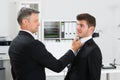 Mature Businessman Gripping Employee's Tie