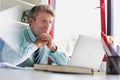 Smiling mature businessman with hands on chin while looking on laptop in office Royalty Free Stock Photo