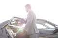 Mature businessman holding car door for female colleague against sky Royalty Free Stock Photo