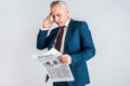 Mature businessman holding head while reading business newspaper isolated