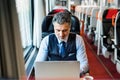 Mature businessman with laptop travelling by train. Royalty Free Stock Photo