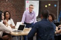 Mature Businessman Leading Office Meeting Of Colleagues Sitting Around Table