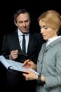 Mature businessman looking at blonde businesswoman signing papers Royalty Free Stock Photo