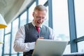 Mature businessman looking at laptop reading improvements sitting near the window in his office Royalty Free Stock Photo