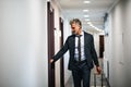 Mature businessman with luggage in a hotel corridor. Royalty Free Stock Photo