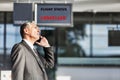 Mature businessman making report on his cancelled flight while standing at his boarding gate in airport