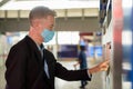 Mature businessman with mask buying ticket at the sky train station Royalty Free Stock Photo