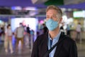 Mature businessman with mask walking off the sky train station Royalty Free Stock Photo