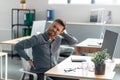 Mature businessman massaging aching neck and back, suffering from pain after computer work, sitting at workplace Royalty Free Stock Photo