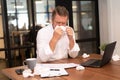 Mature Businessman sick blowing his nose with tissue at office with a lot of used wipes on the desk.Feeling sick and tired