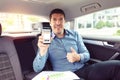 Mature businessman sitting on backseat of car rating taxi services on app while commuting to work Ã¢â¬â business on the go