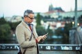 Businessman with smartphone standing on a bridge in city, text messaging. Royalty Free Stock Photo