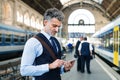 Mature businessman with smartphone on a train station. Royalty Free Stock Photo