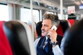 Mature businessman with smartphone travelling by train. Royalty Free Stock Photo