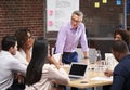 Mature Businessman Standing And Leading Office Meeting Of Colleagues Sitting Around Table Royalty Free Stock Photo