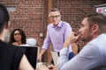 Mature Businessman Standing And Leading Office Meeting Of Colleagues Sitting Around Table Royalty Free Stock Photo