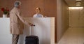 Mature businessman with suitcase checking in at hotel. Royalty Free Stock Photo