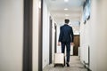 Mature businessman walking with luggage in a hotel corridor. Royalty Free Stock Photo