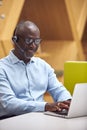 Mature Businessman Wearing Phone Headset Talking To Caller In Busy Customer Services Centre Royalty Free Stock Photo