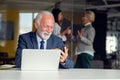 Mature businessman working on laptop. Handsome mature business leader sitting in a modern office Royalty Free Stock Photo