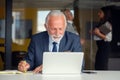 Mature businessman working on laptop. Handsome mature business leader sitting in a modern office Royalty Free Stock Photo