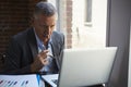 Mature Businessman Working On Laptop By Office Window Royalty Free Stock Photo