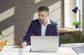 Mature businessman working in the office, using his laptop, and writing something on paper Royalty Free Stock Photo