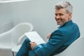 Smiling Mature businessman workingon with documents while sitting in modern coworking