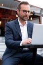 Mature Businessman Working On Laptop By Outdoor Coffee Shop Royalty Free Stock Photo