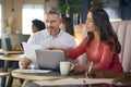 Mature Businesswoman And Businessman Working On Laptop In Informal Seating Area Of Modern Office Royalty Free Stock Photo