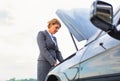 Mature businesswoman looking at breakdown car on road Royalty Free Stock Photo